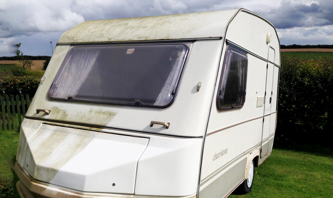 A two berth caravan looking at the front, half has been cleaned with Crud Buster and is gleaming white while the other half is green with algae 